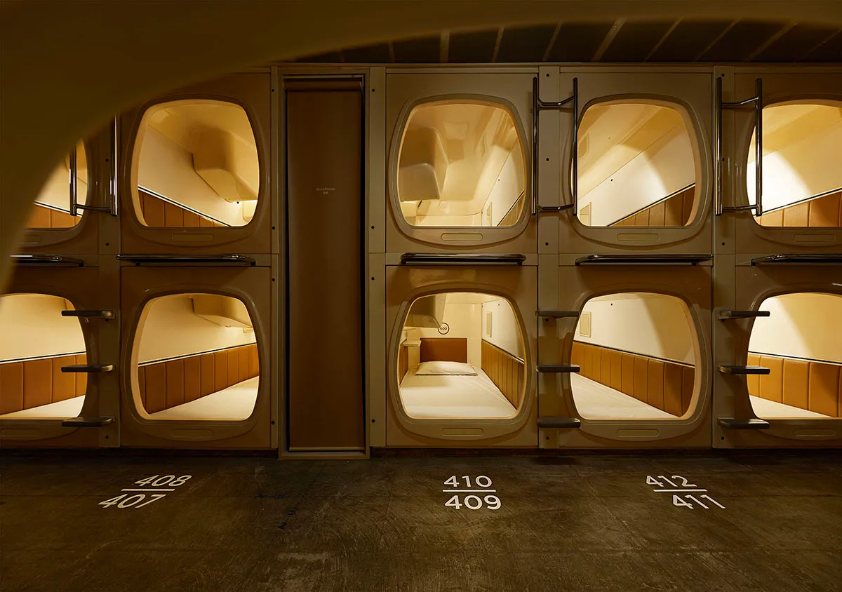 Pale timber capsule openings in two tiers along a quiet corridor