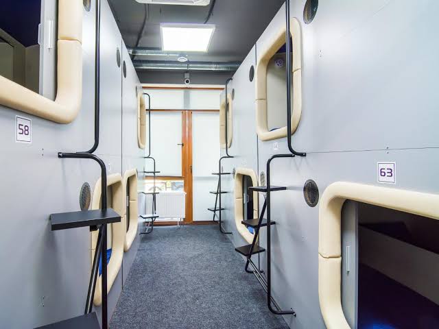 A shared lounge floor beneath rows of compact sleeping berths