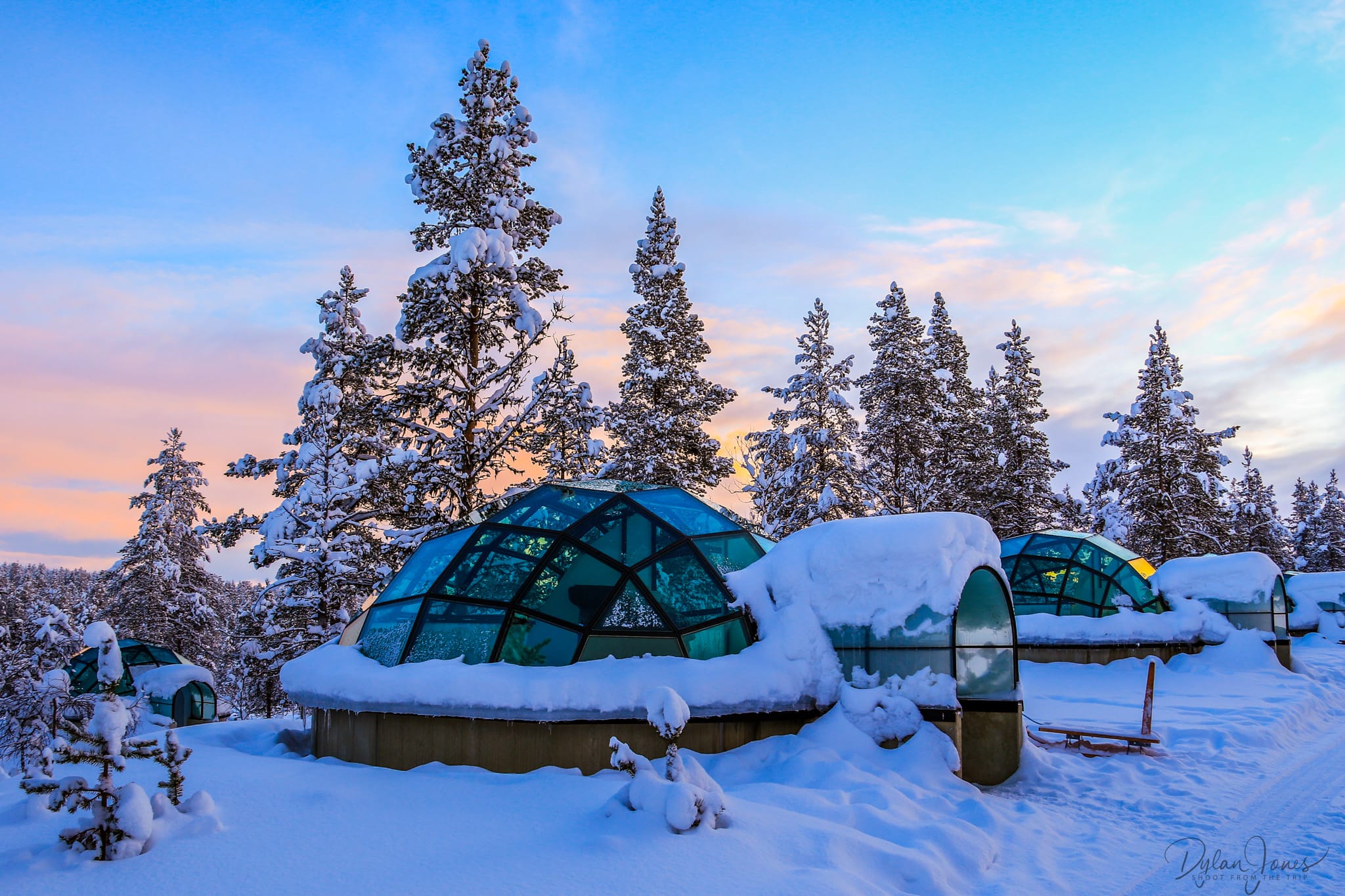 Snow igloos and heated glass igloos standing apart among northern forest